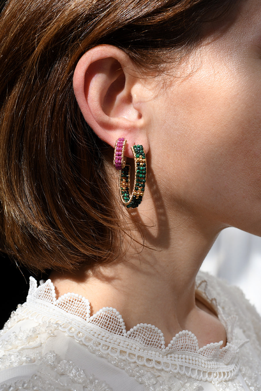 Close-up of a person wearing colorful hoop earrings with a blurred background