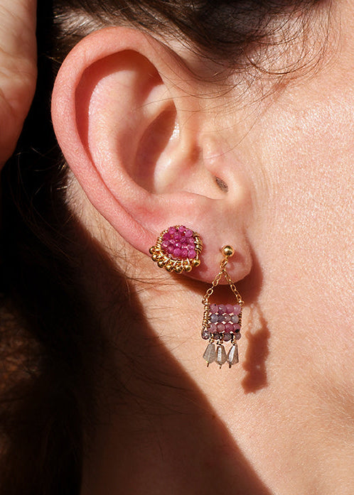 Close-up of a person wearing pink earrings with a neutral background