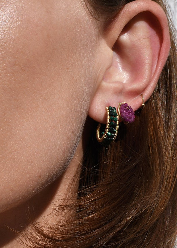 Close-up of a person wearing a necklace and earrings with a neutral background