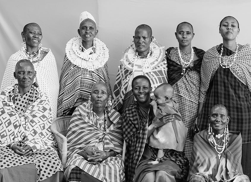 Group of Maasai ladies wearing traditional shukas (cloths), beaded necklaces, gold bangles and beaded discs.