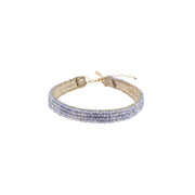 Beaded tanzanite bracelet with beige leather strap on a white background